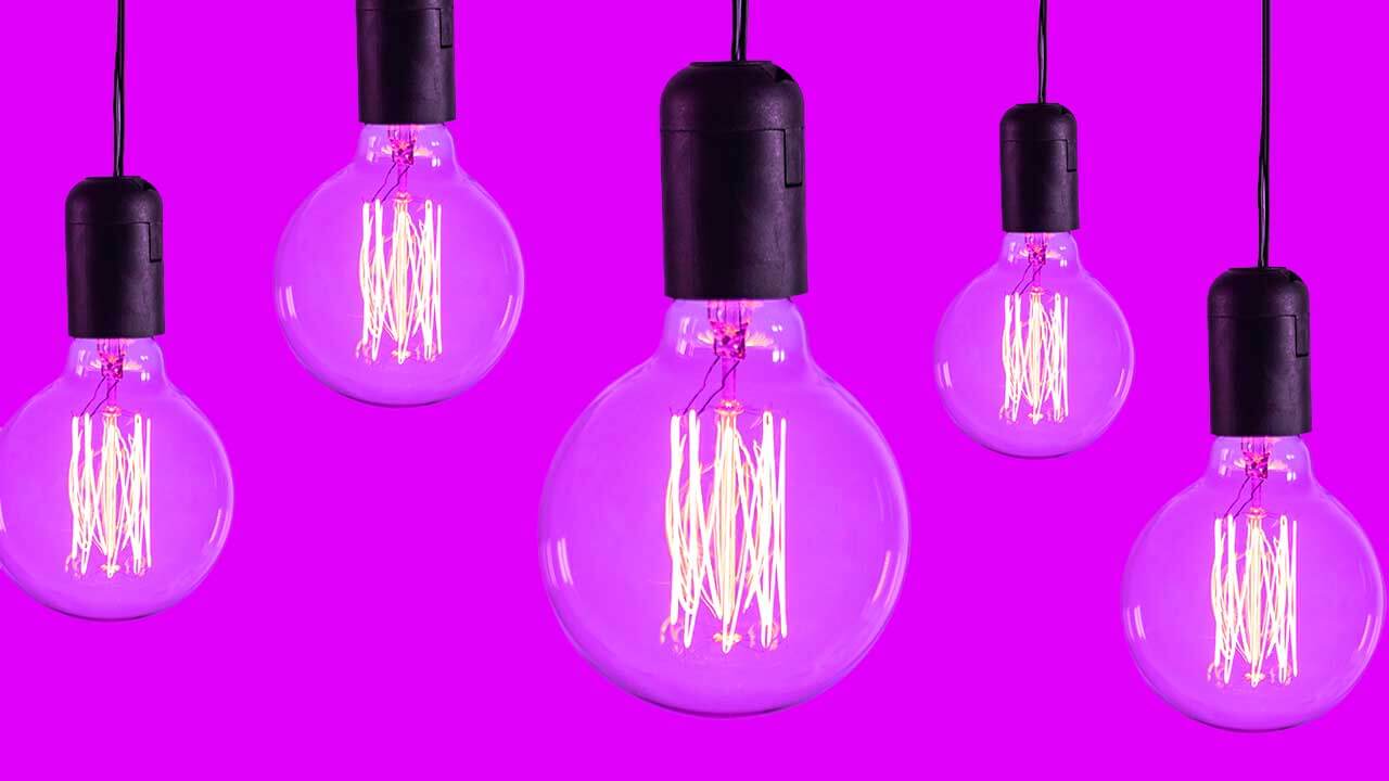 Five vintage-style Edison light bulbs with glowing filaments hanging against a solid purple background.