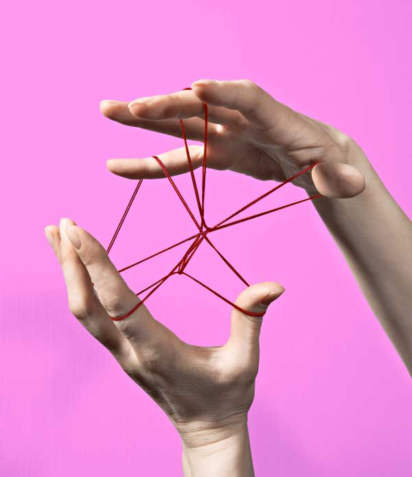 Two hands modeling a network of red string on a purple background, symbolizing the generation of synthetic data to accurately mirror human consumer behavior in market research