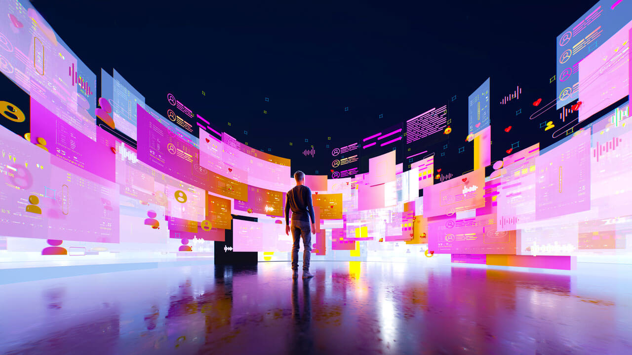 A wide digital illustration showing a person standing from behind on a reflective floor, looking up at a vast, curved panoramic wall of floating digital interfaces. The glowing virtual screens are filled with data charts, user profile avatars, social media elements, and text bubbles in vibrant hues of pink, orange, and purple against a dark sky background.